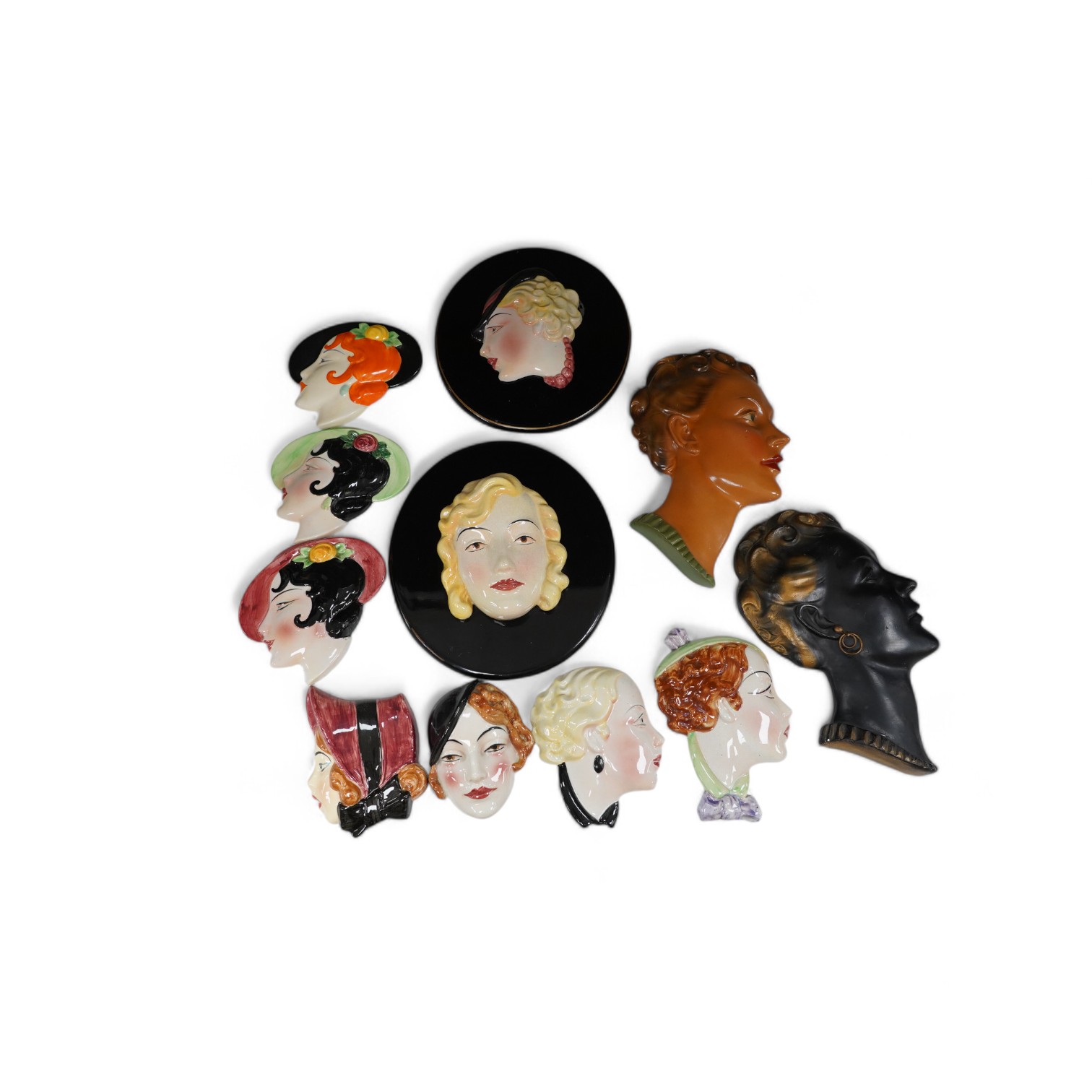 Six Art Deco style composition and pottery wall masks, largest 30cm high. Condition - fair, one mask detached from plaque